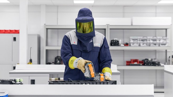 Técnico manipulando baterias de íons de lítio enquanto utiliza equipamento de proteção individual completo